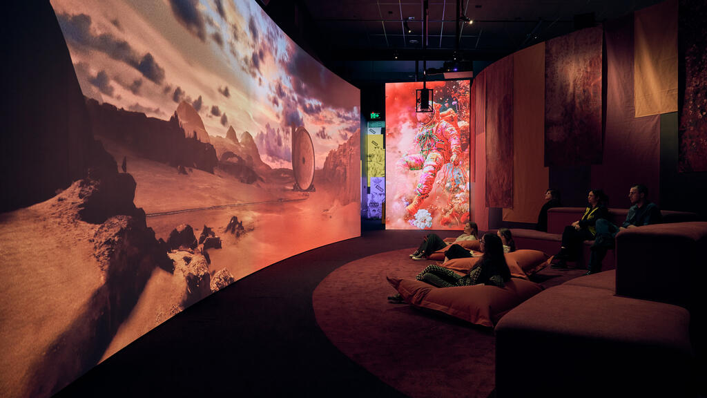 People sit on beanbags in low-lit space watching large screen